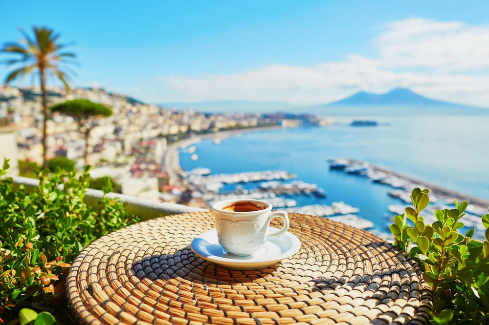 Un café devant un balcon donnant sur les plages de Naples